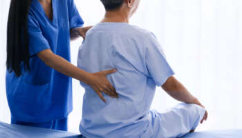 Female physical therapist doing physical therapy for adult patient at hospital room.