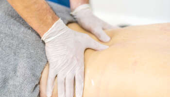 Physiotherapist doing a massage with gloves. Reopening with physiotherapy safety measures in the Covid-19 pandemic. Osteopathy, therapeutic chiromassage