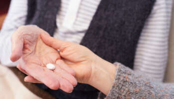 Hands of senior patient and caregiver with medication