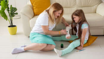 Mother and daughter drawing picture on bandage using paints. Play therapy concept