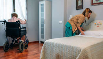 Caregiver making the bed of an elderly patient in a nursing home