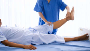 Physical therapist doing physical therapy for adult patient at hospital room.